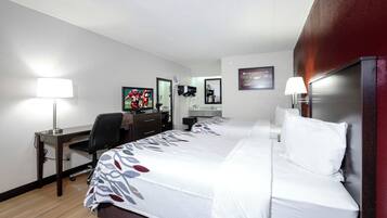 Habitación de hotel con dos camas, un escritorio, una silla, un televisor y un baño.