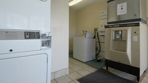 Une laverie équipée de sécheuses industrielles et d’une machine à glaçons.