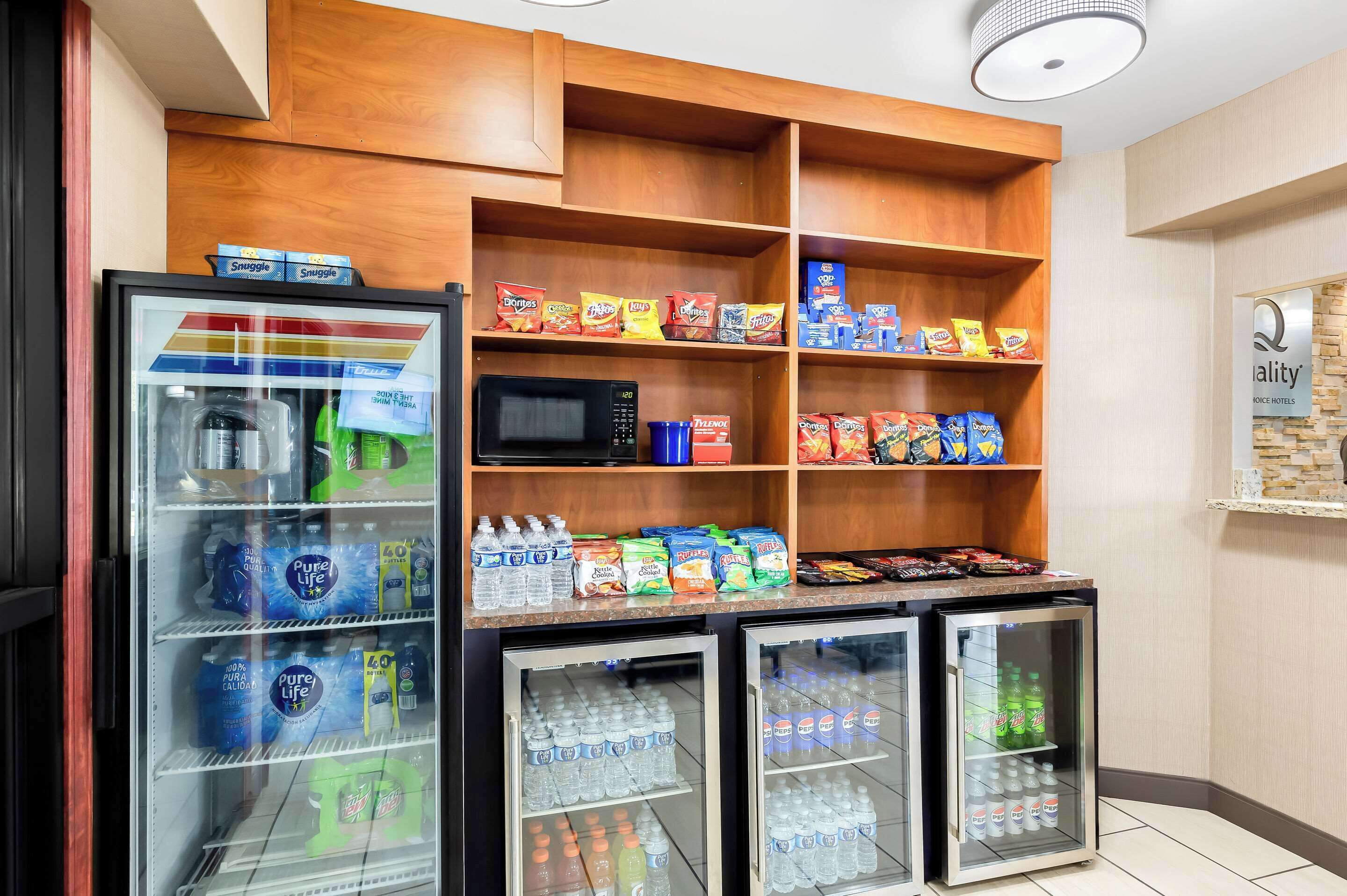Un refrigerador con aperitivos y bebidas, que incluye papas fritas, agua embotellada y refrescos.