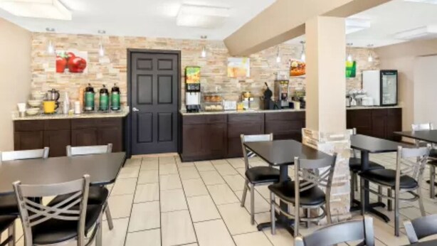 A modern restaurant with a stone wall backsplash, dark wooden cabinets, and a variety of seating options including tables and chairs. - Quality Inn Middleburg Heights near Cleveland Airport (Middleburg Heights)