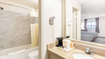 Une salle de bain avec une douche en marbre, des toilettes, un lavabo avec un miroir et un sèche-cheveux fixé au mur.