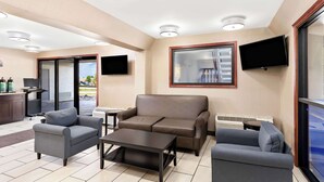 A modern hotel room with a sofa, armchairs, a coffee table, and a flat-screen TV mounted on the wall. - Quality Inn Middleburg Heights near Cleveland Airport (Middleburg Heights)