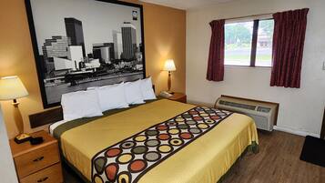 Habitación de hotel con cama, mesita de noche, lámpara, ventana con cortinas y aire acondicionado instalado en la pared.