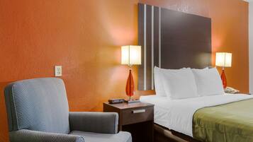 A hotel room with a bed, a nightstand, a chair, and two lamps.