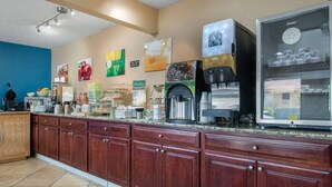 A coffee station with a coffee machine, a refrigerator with beverages, and a counter with various food items. - Quality Inn Columbus - East (Columbus)