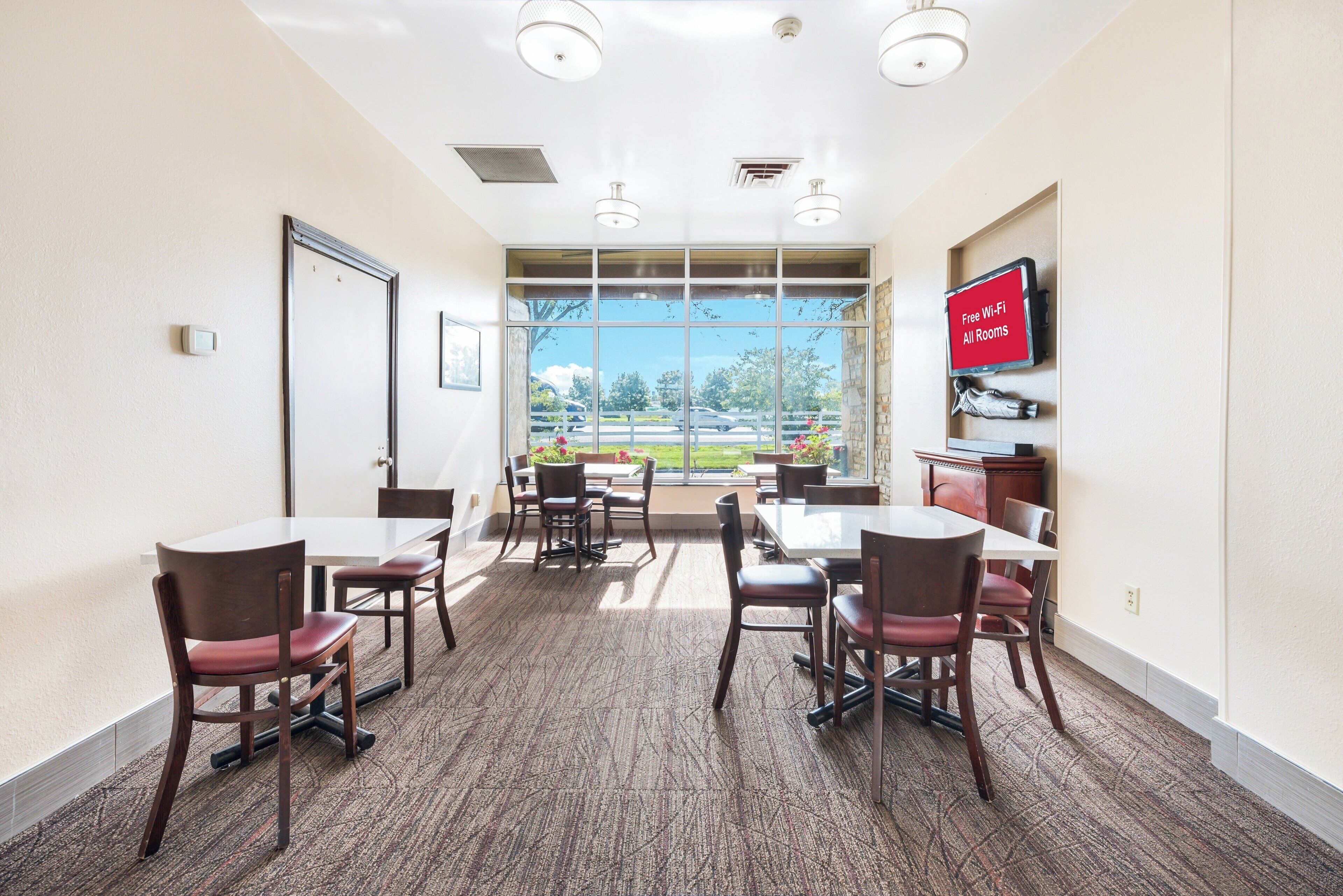 A conference room with a large window, multiple tables, and chairs.
