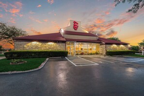 A Red Roof Inn with a stone facade, a red roof, and a parking lot. - Red Roof Inn Columbus - Grove City (Grove City)