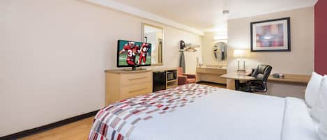 A hotel room with a bed, a desk, a chair, a television, a mirror, and a painting on the wall.