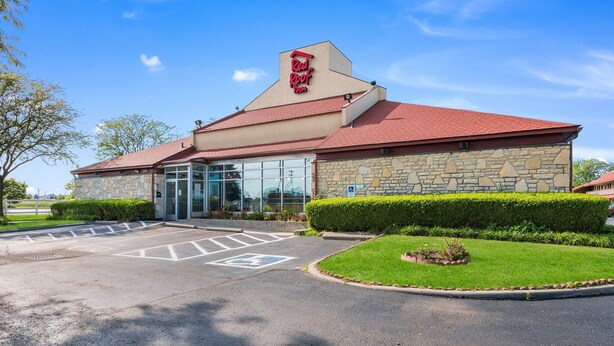 A Red Roof Inn with a stone facade, a red roof, and a glass entrance.