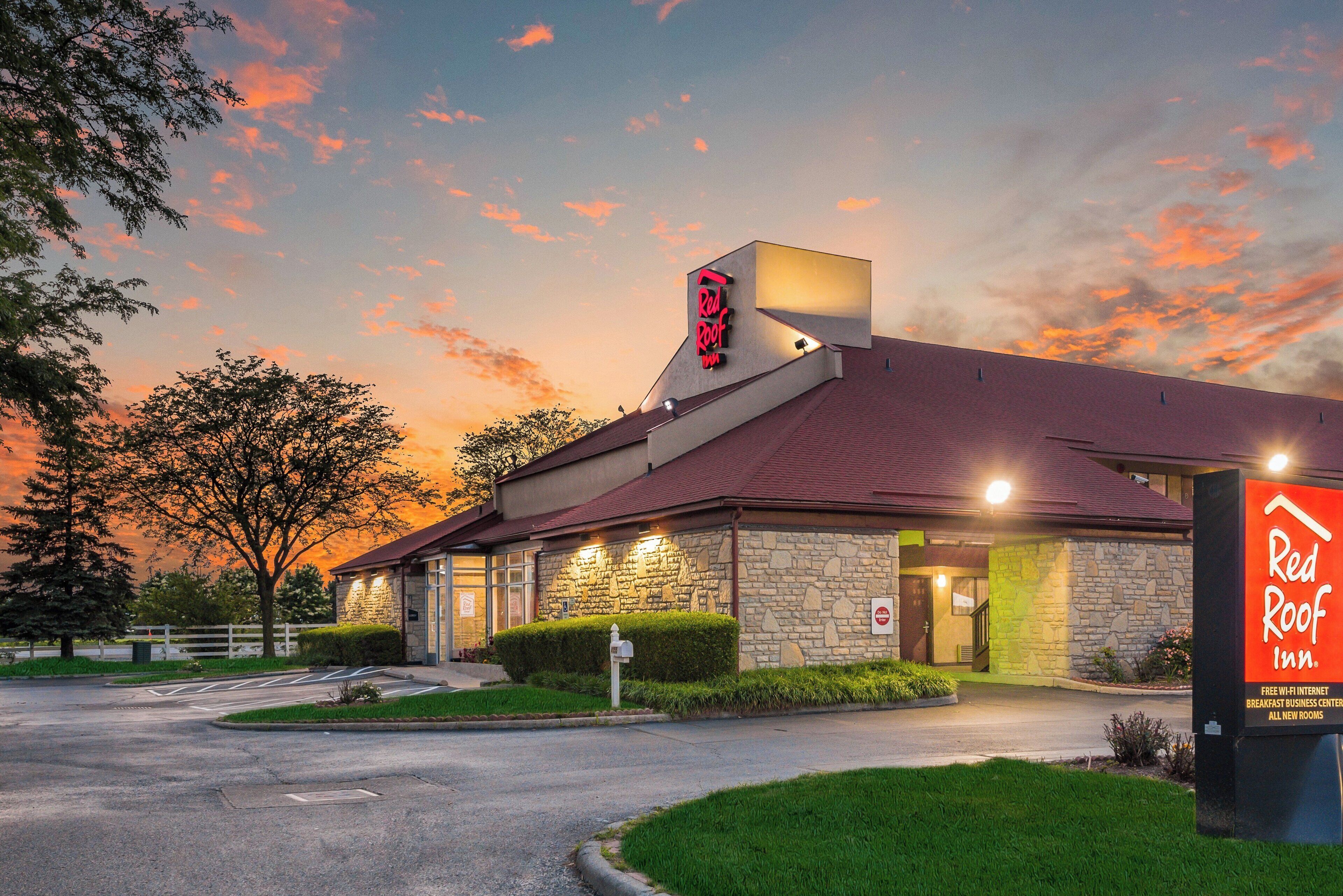 A Red Roof Inn with a stone facade, a sloped roof, and a signboard.