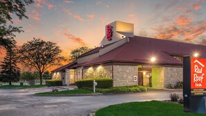 Um Red Roof Inn com fachada de pedra, telhado inclinado e uma placa de identificação.