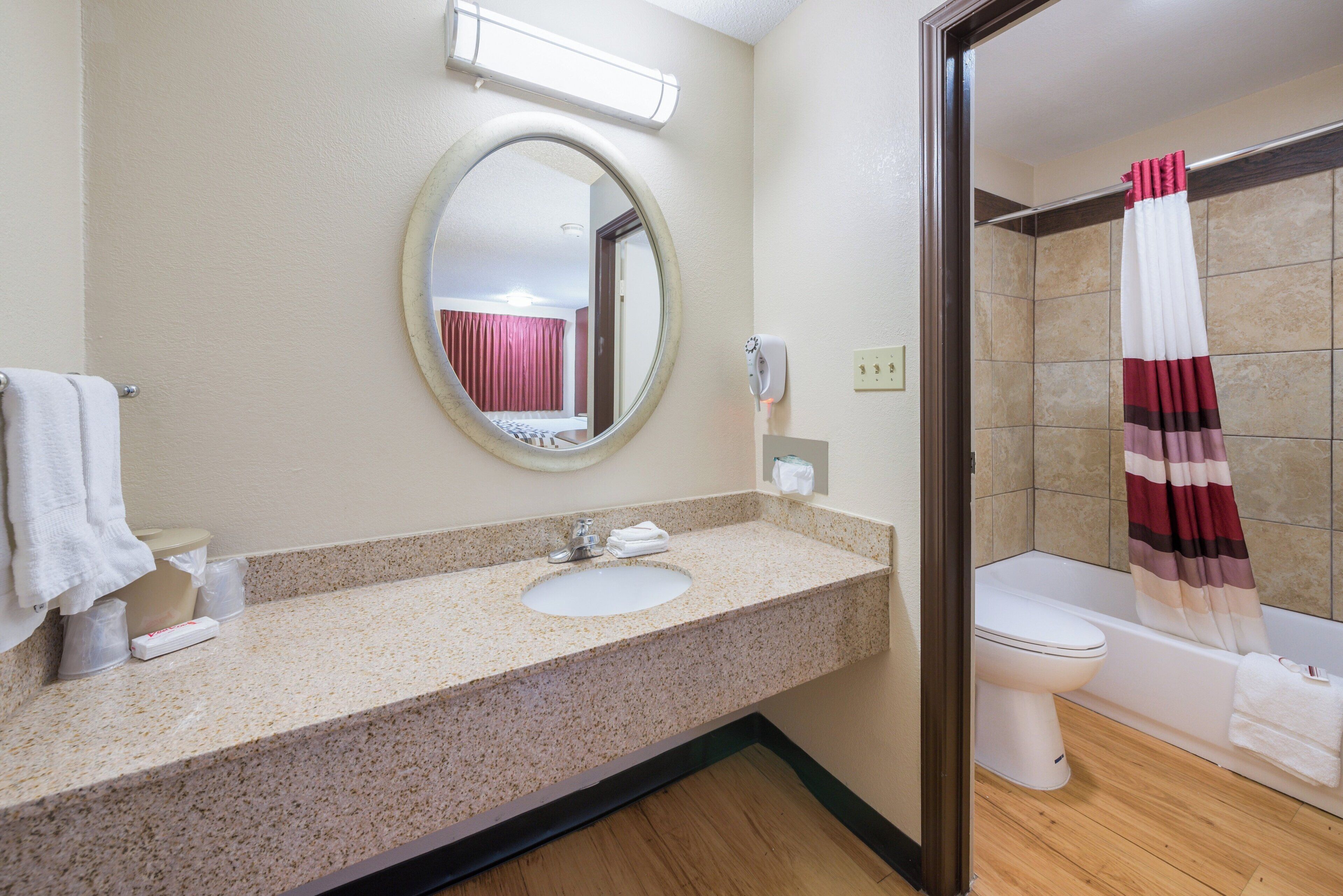 Un baño con lavamanos, espejo, inodoro y ducha.