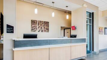 A reception desk with a check-in/out sign, a digital display, and a 'Free Wi-Fi All Rooms' sign.