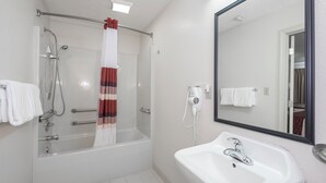 Un baño con bañera, ducha, lavamanos y espejo.
