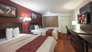 Habitación de hotel con dos camas, un escritorio, un televisor y una puerta.
