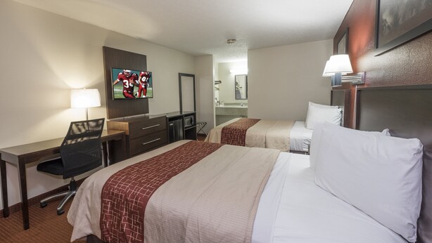 A hotel room with two beds, a desk, a chair, a TV, and a bathroom visible through an open door. - Red Roof Inn Columbus Northeast - Westerville (Westerville)