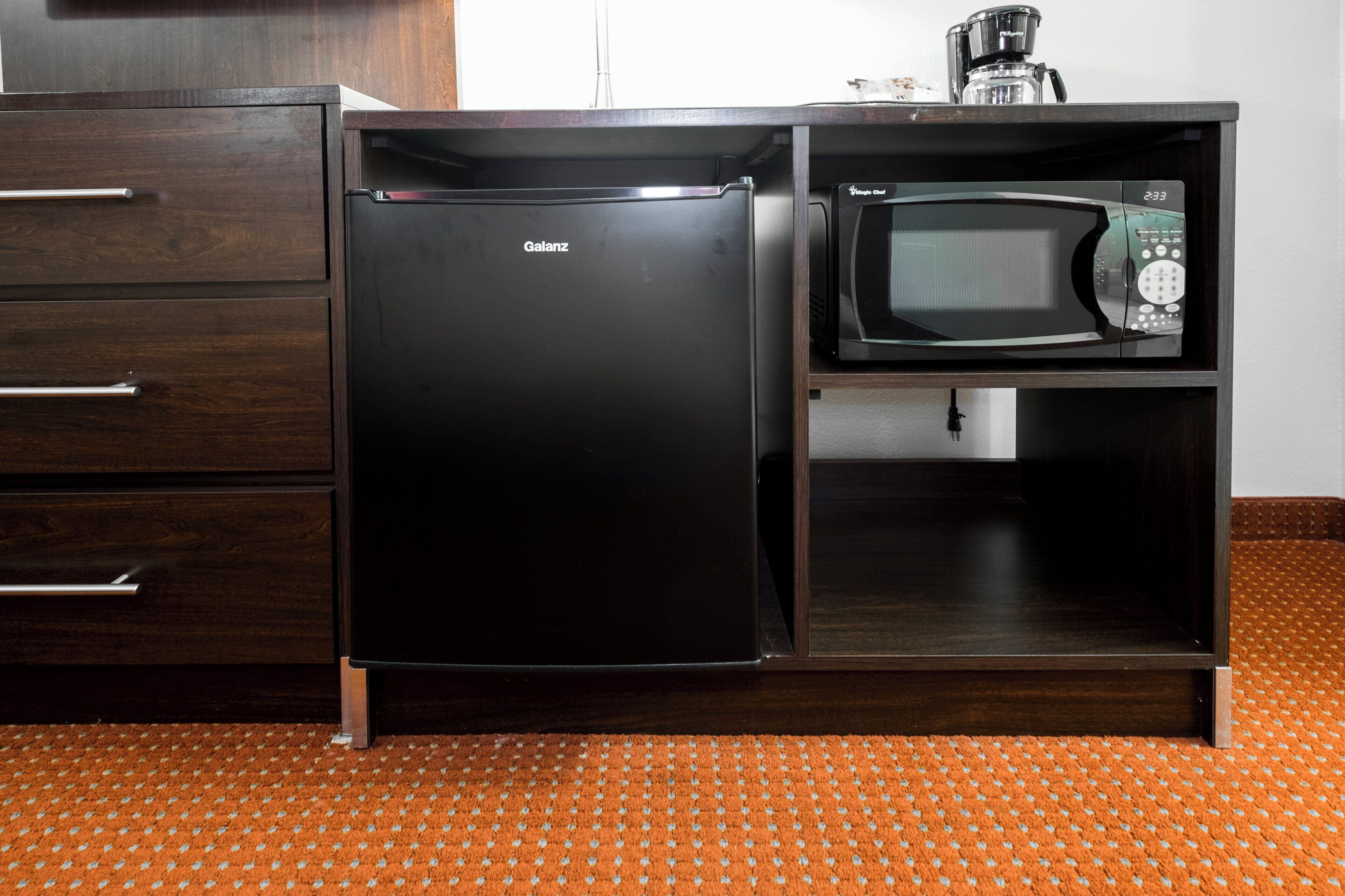 A compact kitchen with a refrigerator, microwave, and coffee maker.