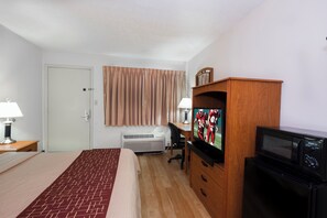 A hotel room with a bed, a desk, a television, and an air conditioning unit. - Red Roof Inn Columbus Northeast - Westerville (Westerville)