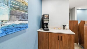 Una macchina da caffè su un bancone con un quadro appeso al muro.