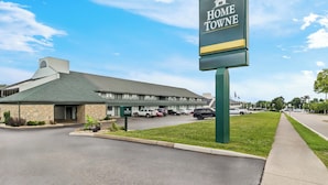 Un hotel llamado "Home Towne" con fachada de piedra, techo verde y un estacionamiento con varios coches.