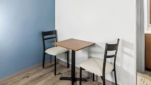 Un pequeño comedor con una mesa de madera y dos sillas, una pared azul y un armario de madera.