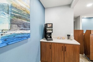 A coffee machine on a counter with a painting on the wall. - HomeTowne Studios by Red Roof Florence, KY-Cincinnati Airport (Florence)