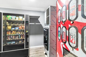 A vending machine with various snacks and a Coca-Cola dispenser. - HomeTowne Studios by Red Roof Florence, KY-Cincinnati Airport (Florence)