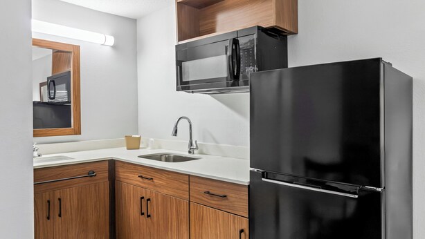 Una cucina moderna con mobili in legno, un frigorifero in acciaio inossidabile, un forno a microonde e un lavello.