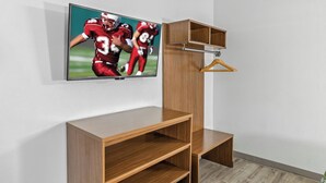 Una camera moderna con un'unità portaoggetti in legno, una TV a parete e una gruccia in legno.