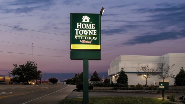 Un cartel de Home Towne Studios con un edificio moderno al fondo.