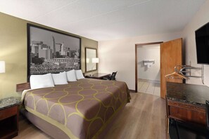 A hotel room with a large bed, a desk, a chair, a TV, and a bathroom.