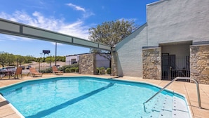 A swimming pool with lounge chairs and a covered area, surrounded by stone walls and a clear sky. - Super 8 by Wyndham Fort Mitchell Cincinnati Area (Fort Mitchell)