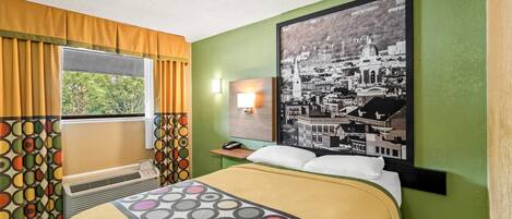 A hotel room with a bed, a window with curtains, a wall-mounted lamp, and a large cityscape poster.