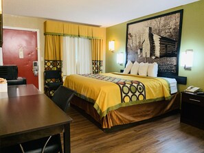 A hotel room with a bed, a desk, a chair, a red door, and a wall with a picture. - Super 8 by Wyndham Cincinnati/Springdale OH (Cincinnati)