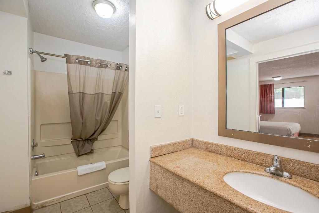 A bathroom with a bathtub, toilet, and a sink with a granite countertop.