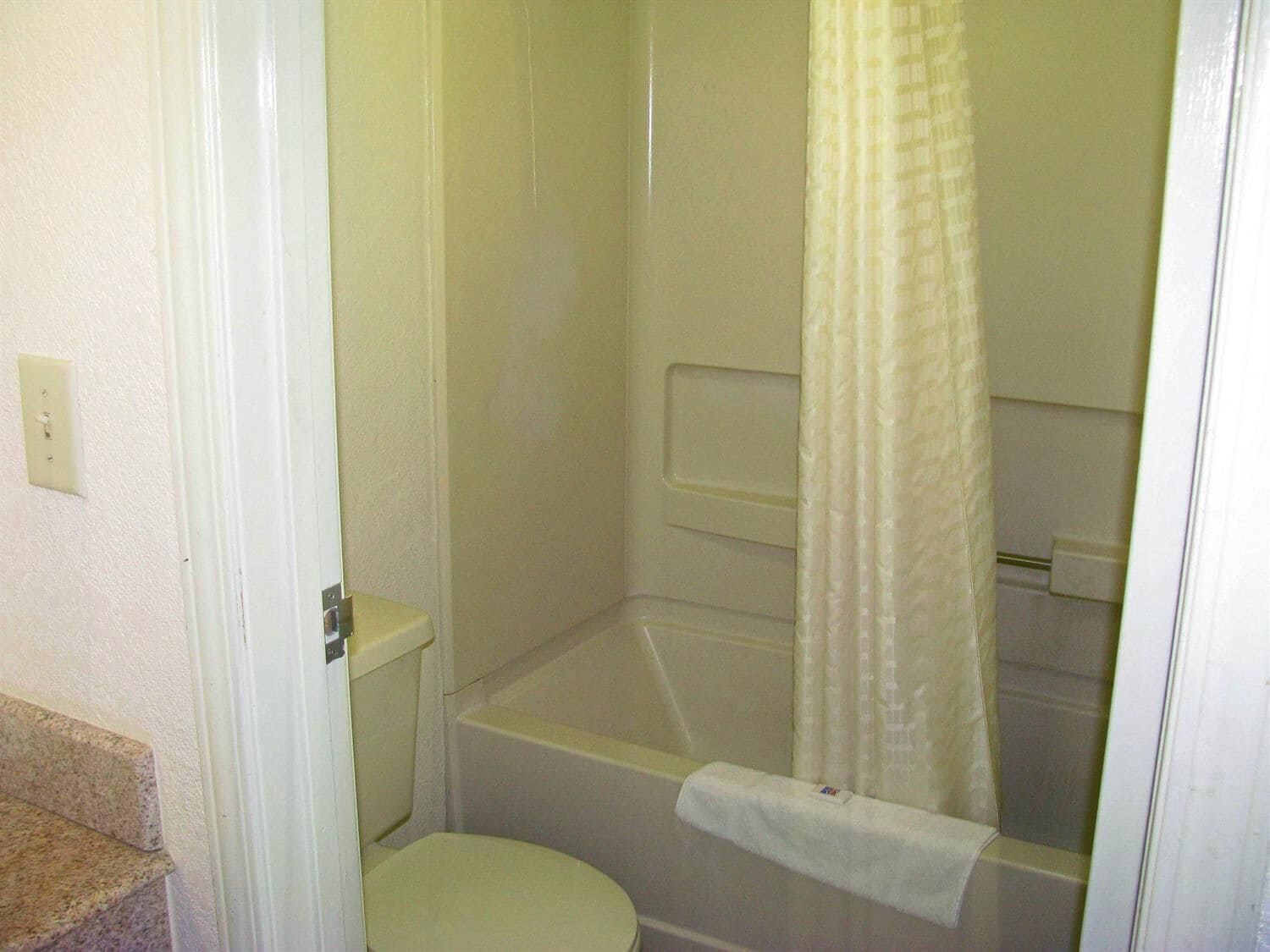 A small, white bathroom with a toilet, a bathtub, and a shower curtain.