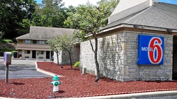 Situated near a parking lot, this motel offers a convenient stay with a stone exterior and nearby trees.