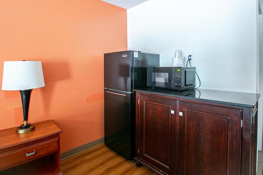 Una kitchenette equipada con refrigerador, microondas y un armario de madera.