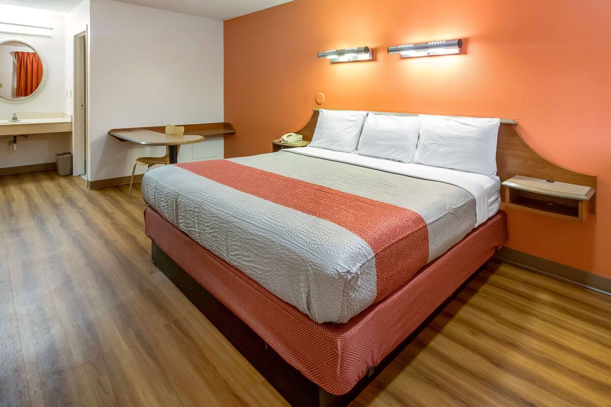 A hotel room with a bed, a desk, and a chair.