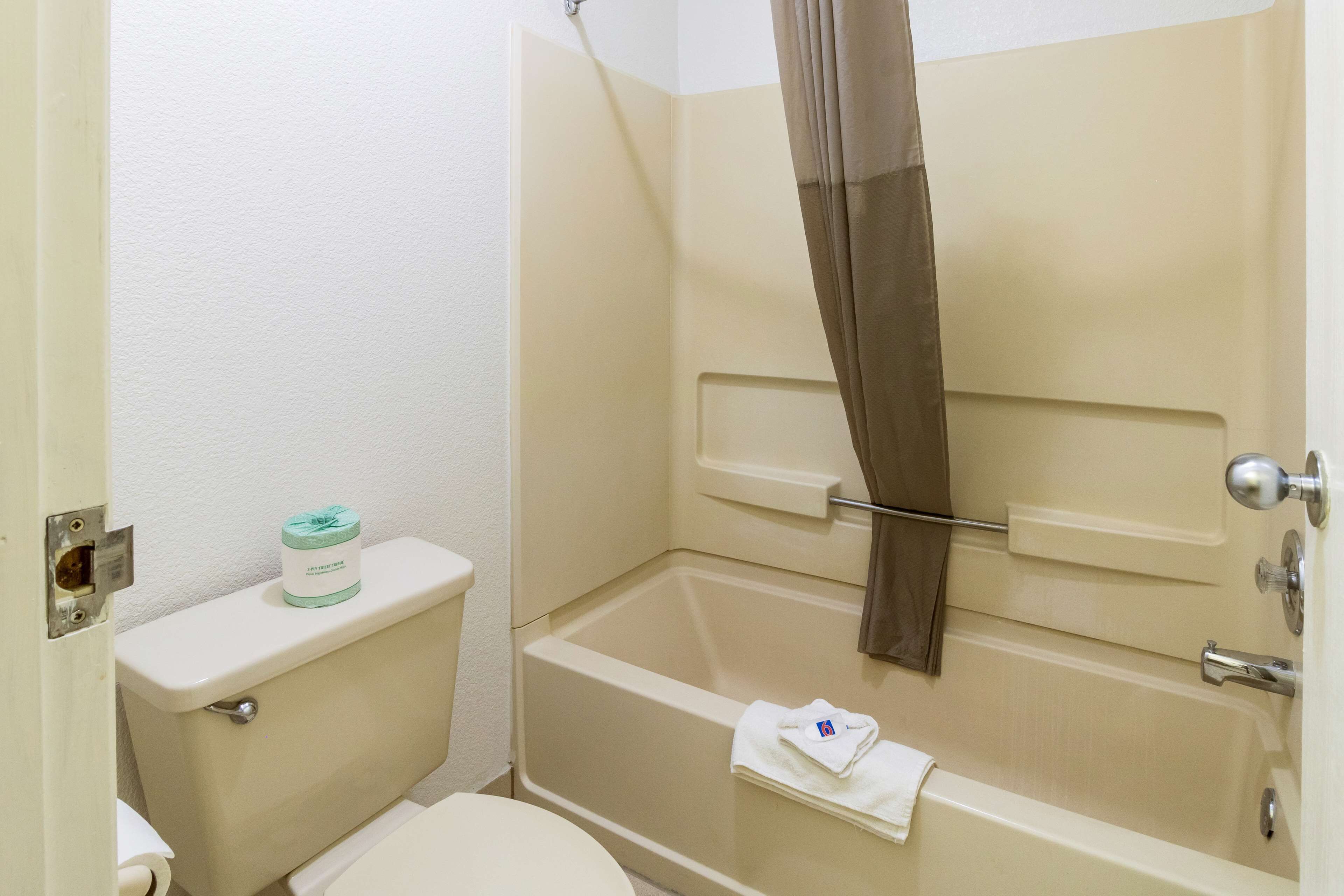 Et lille badeværelse med toilet, badekar og bruseforhæng.
