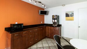 A compact kitchen with a microwave, coffee machine, and a flat-screen TV on the wall. - Motel 6 Dayton, OH - Englewood (Englewood)