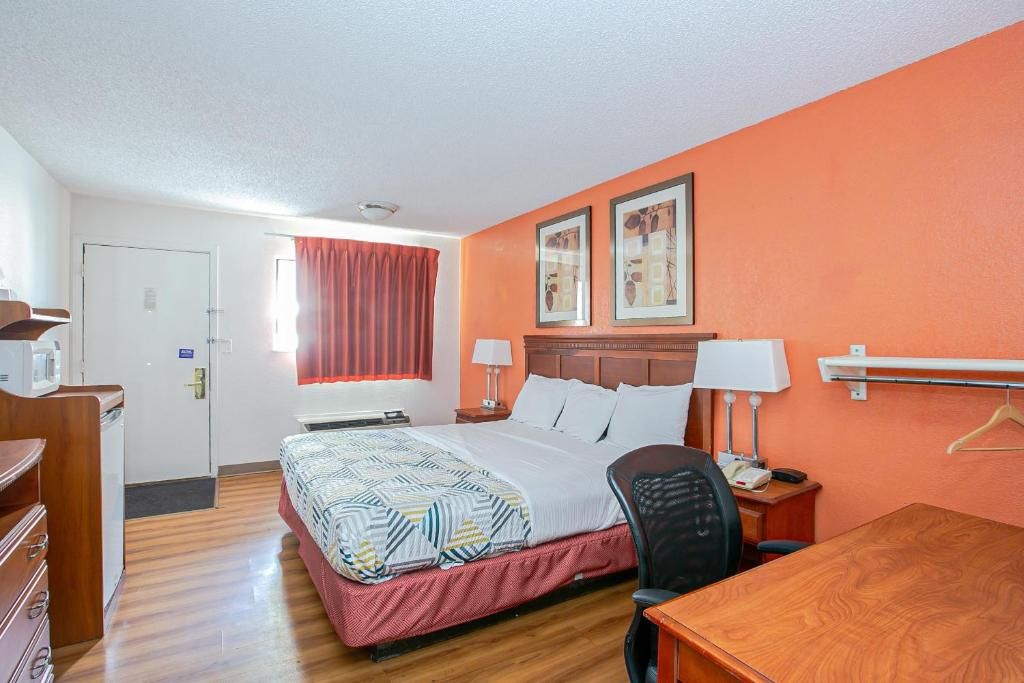 Une chambre d’hôtel comprenant un lit, des tables de chevet, un bureau, une chaise et une armoire.