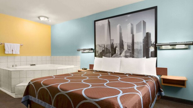 Ein Hotelzimmer mit einem großen Bett, einer Badewanne und einem Stadtbild an der Wand.