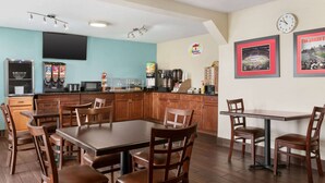 Eine moderne Küche mit Holzausstattung, einem Esstisch und Stühlen. Es gibt eine Kaffeemaschine, eine Mikrowelle und einen Kühlschrank.