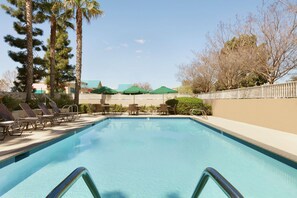 Una piscina al aire libre, sombrillas, sillones reclinables de piscina