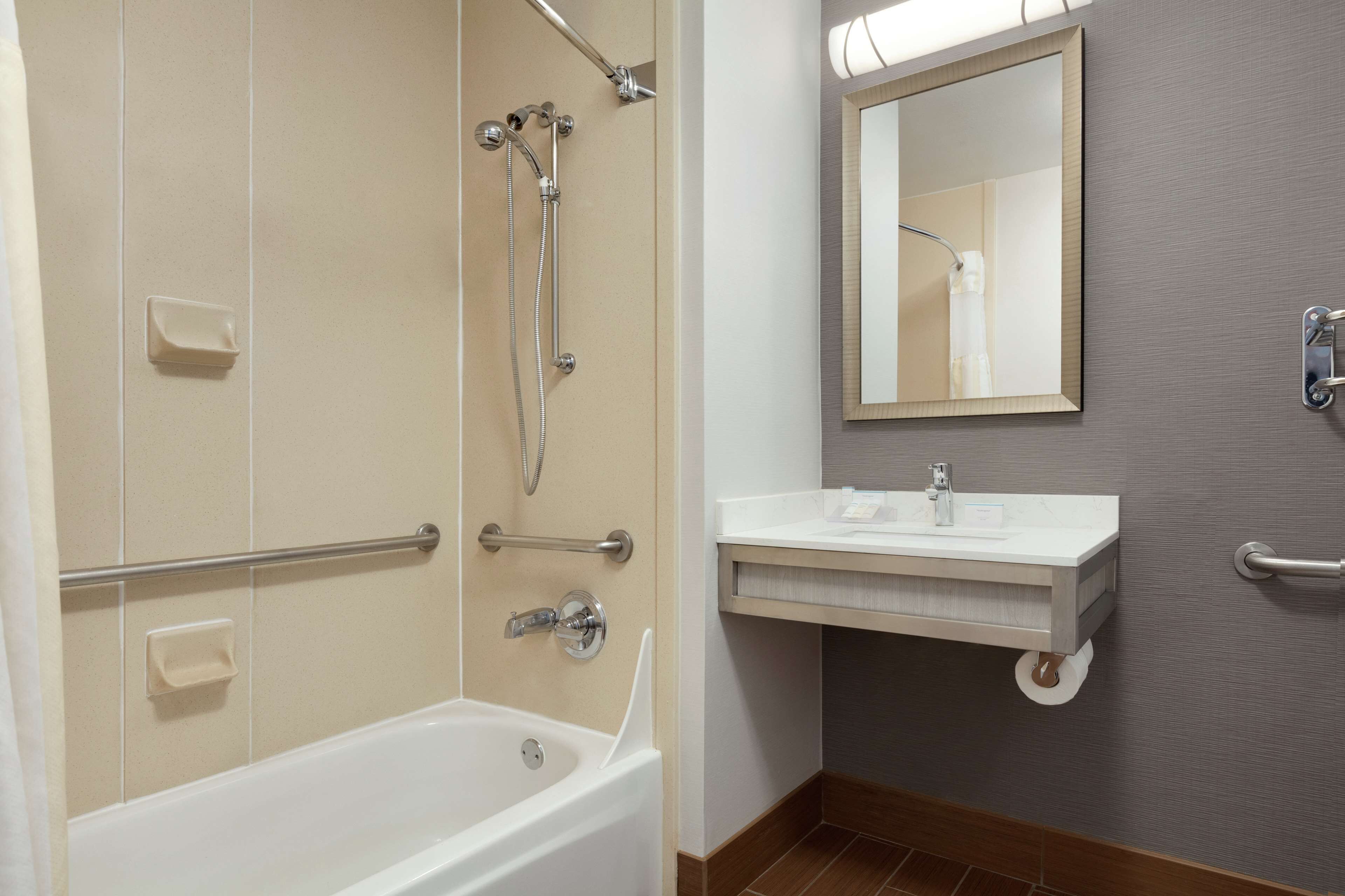 A bathroom with a bathtub, a shower, a sink with a mirror, and a towel rack.