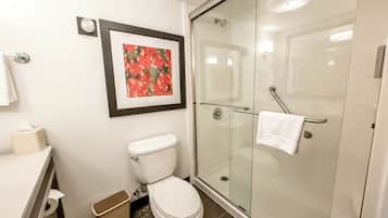 A modern bathroom with a toilet, a glass shower enclosure, and a framed picture on the wall.