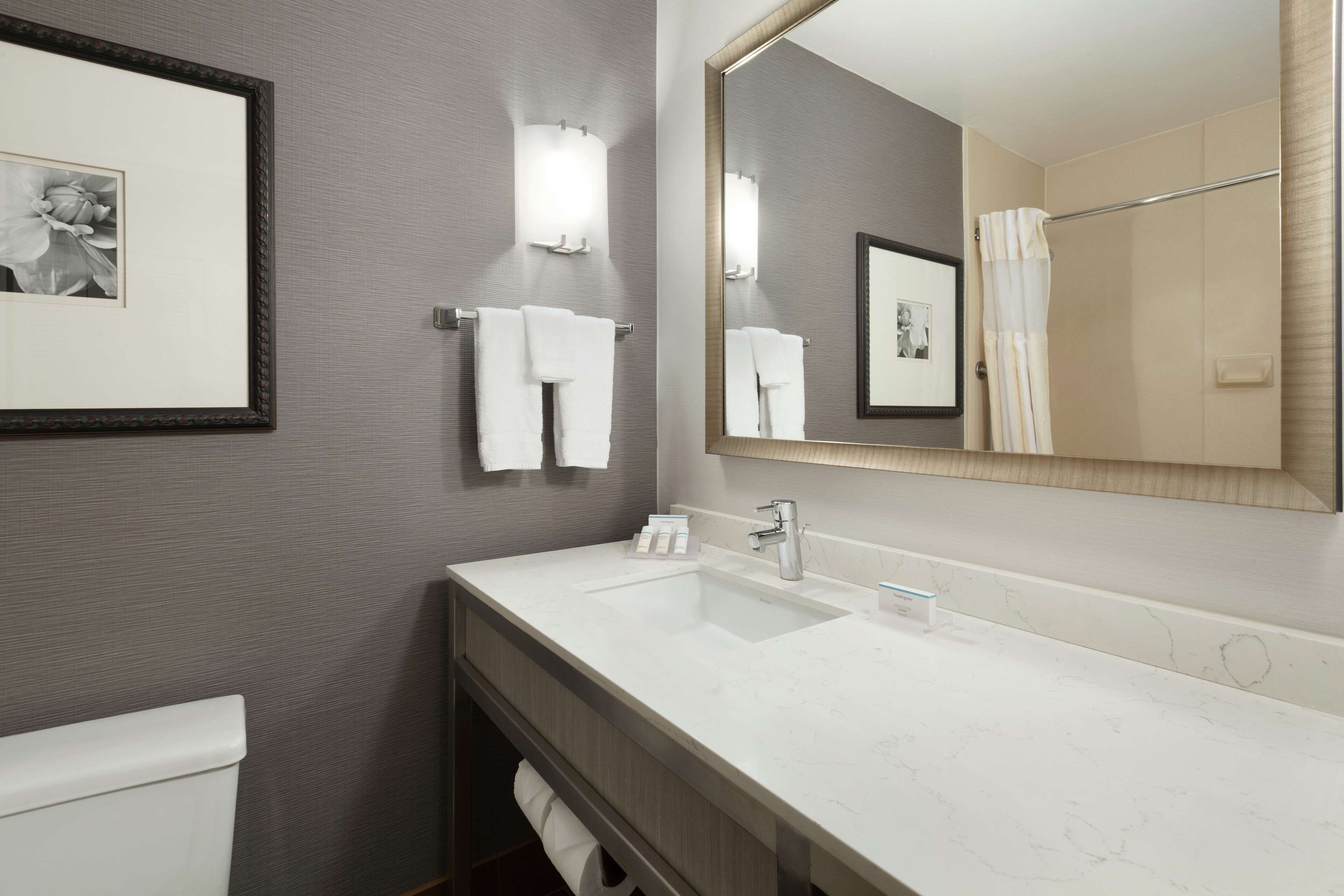 Een moderne badkamer met een grote spiegel, een witte wastafel en een toilet.