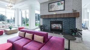 A spacious living room with a fireplace, large windows, and modern furnishings.
