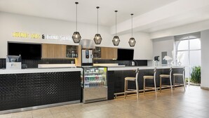 A modern bar area with a black textured counter, three hanging pendant lights, and a refrigerated display. - Fiesta Inn Express Nuevo Laredo (Nuevo Laredo)